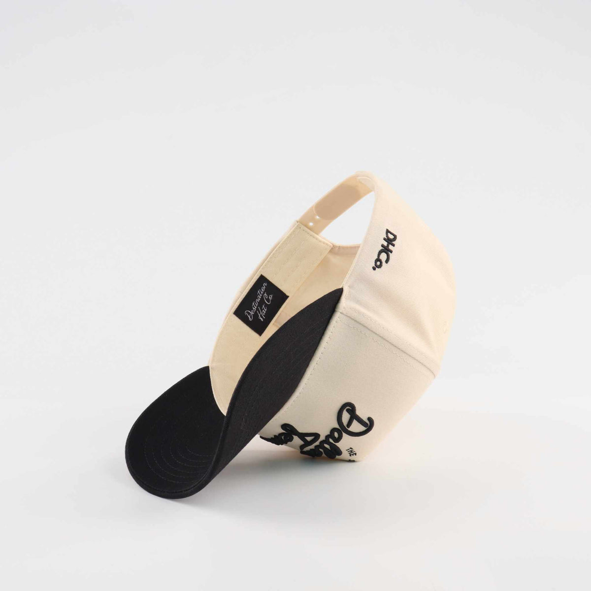 The Dallas Script Hat in beige and black, featuring a curved brim and script logo embroidery