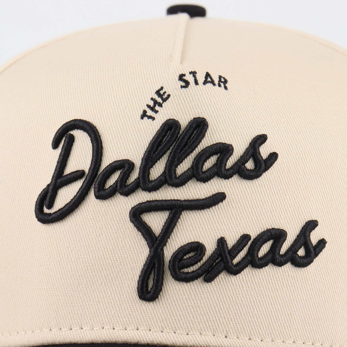 The Dallas Script Hat in beige with raised black Dallas Texas script embroidery and The Star lettering