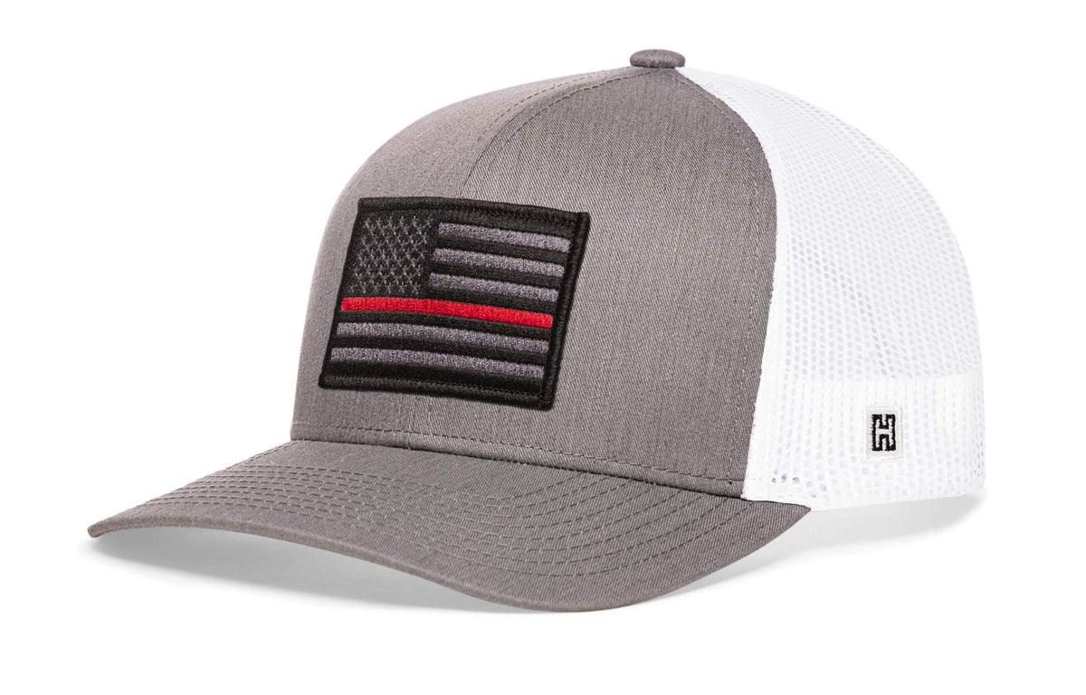Thin Red Line Trucker Hat with grey front, white mesh back, and embroidered black and grey flag patch with a red line stripe.