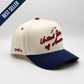 U.S.A Script Hat in cream and navy cotton, featuring red embroidered “United States of America” script and curved brim